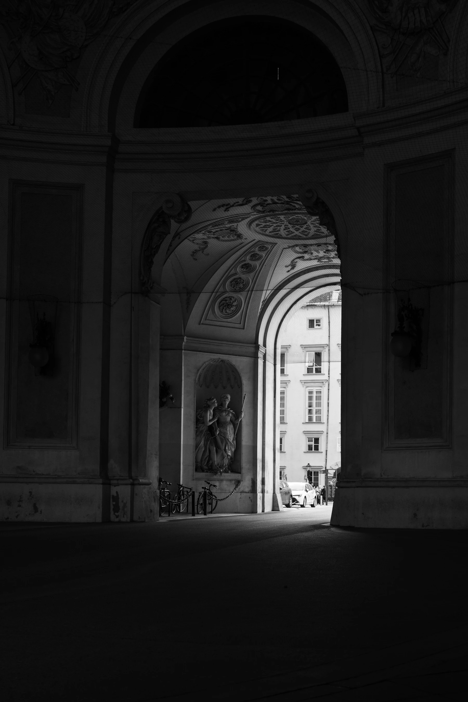 An ornate archway framing a sunlit historic building in Vienna