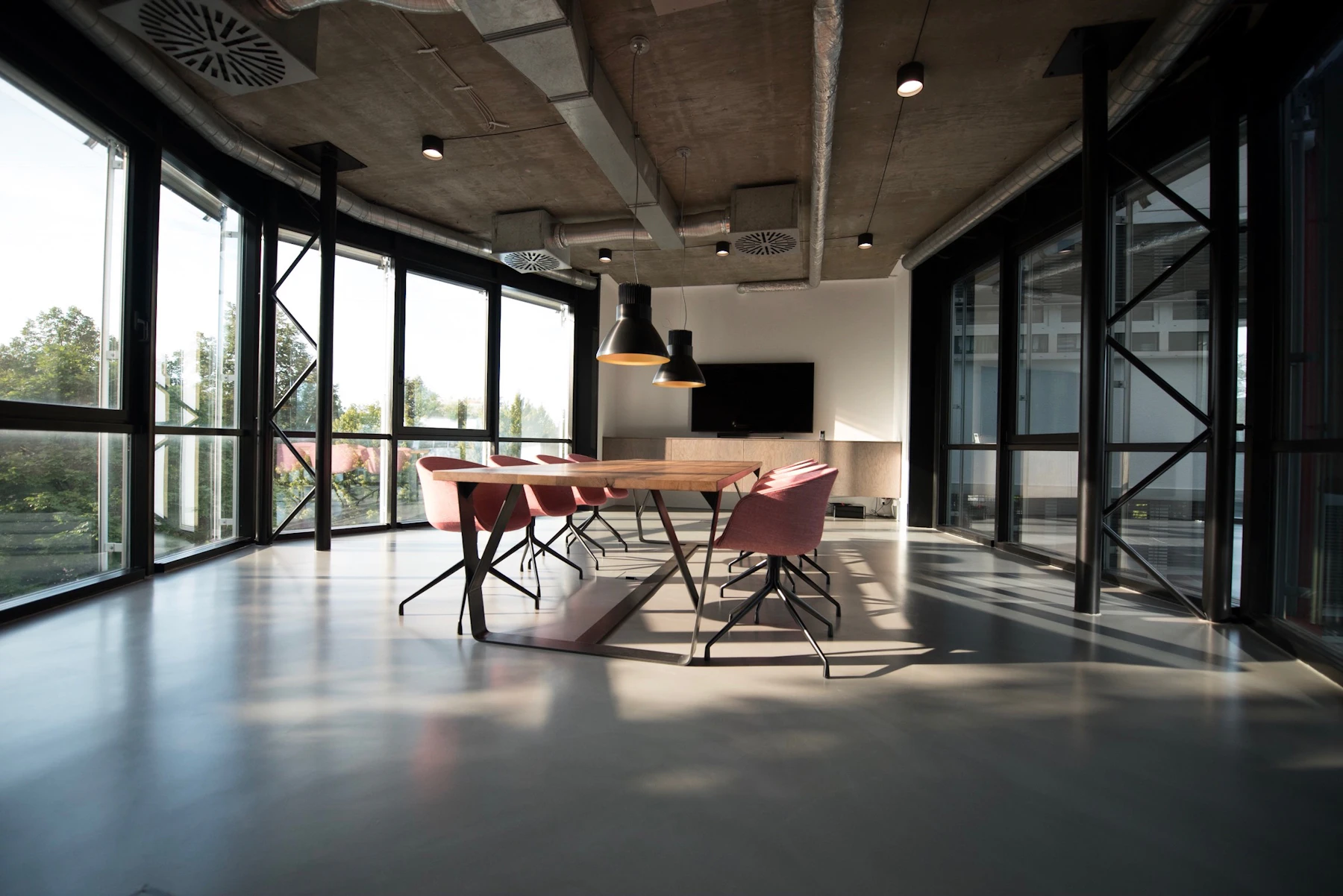 Glass-walled meeting room with a long table and natural light