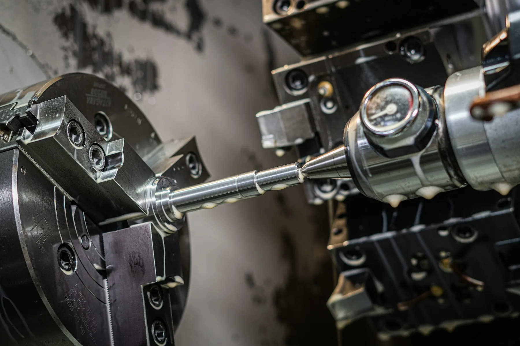 A precision-machined shaft held in the chuck of a CNC lathe in Mainaschaff, Germany