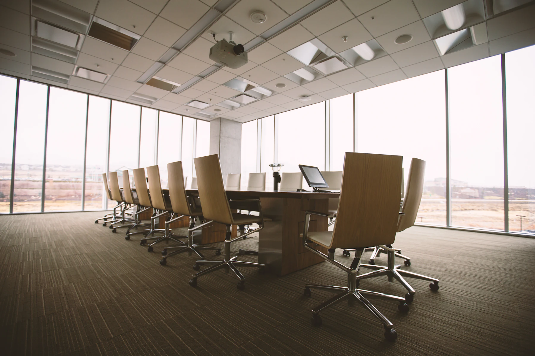 Sunlit boardroom with a long walnut conference table and leather chairs