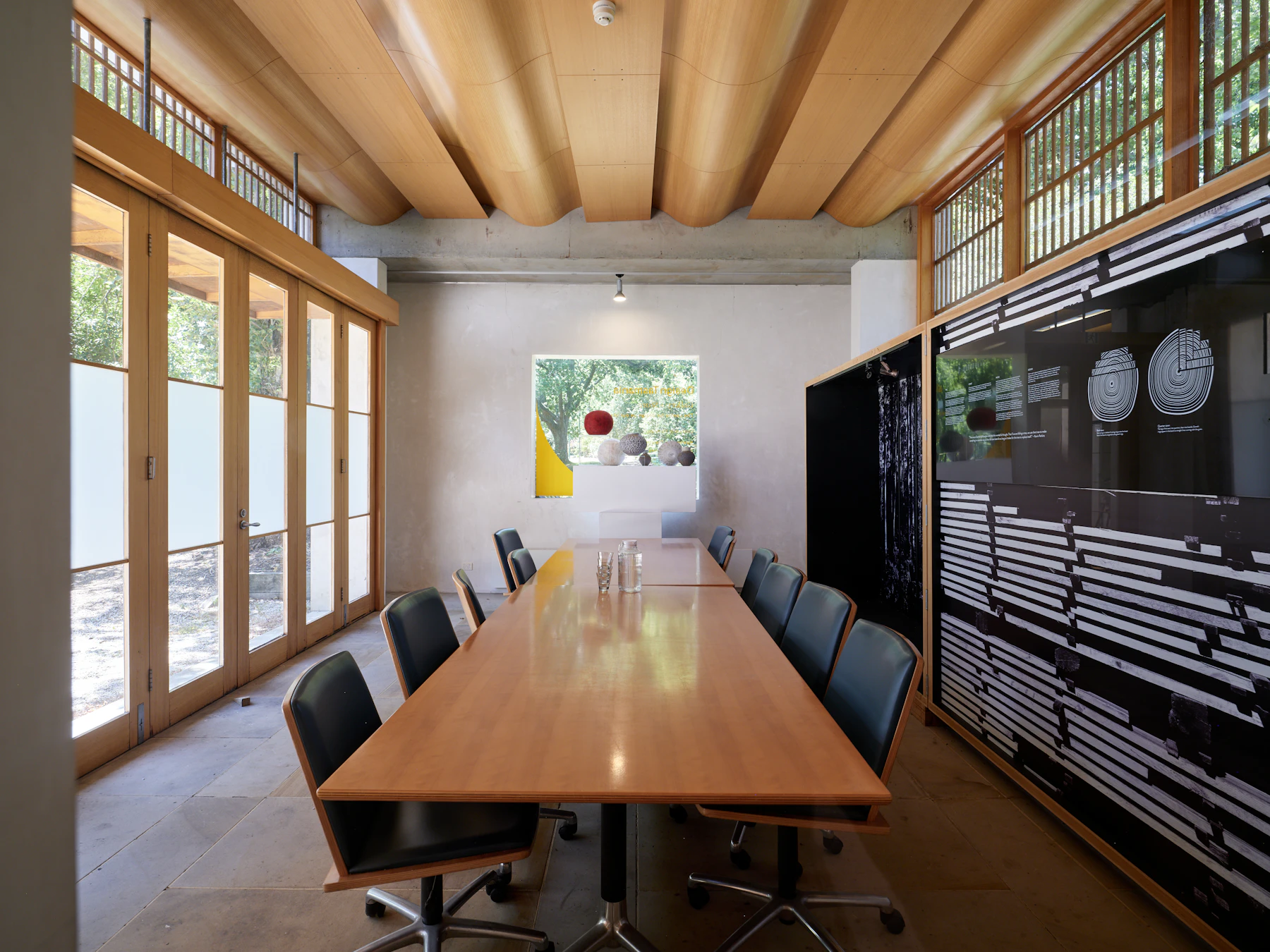 A sunlit meeting room with timber ceiling beams and a long wooden conference table at Design Tasmania