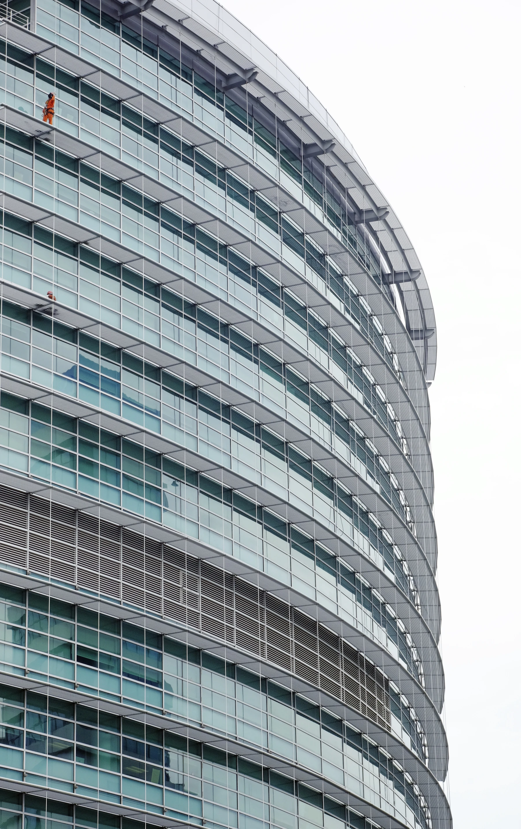 Curving glass office facade with pale blue glazing and horizontal structural lines