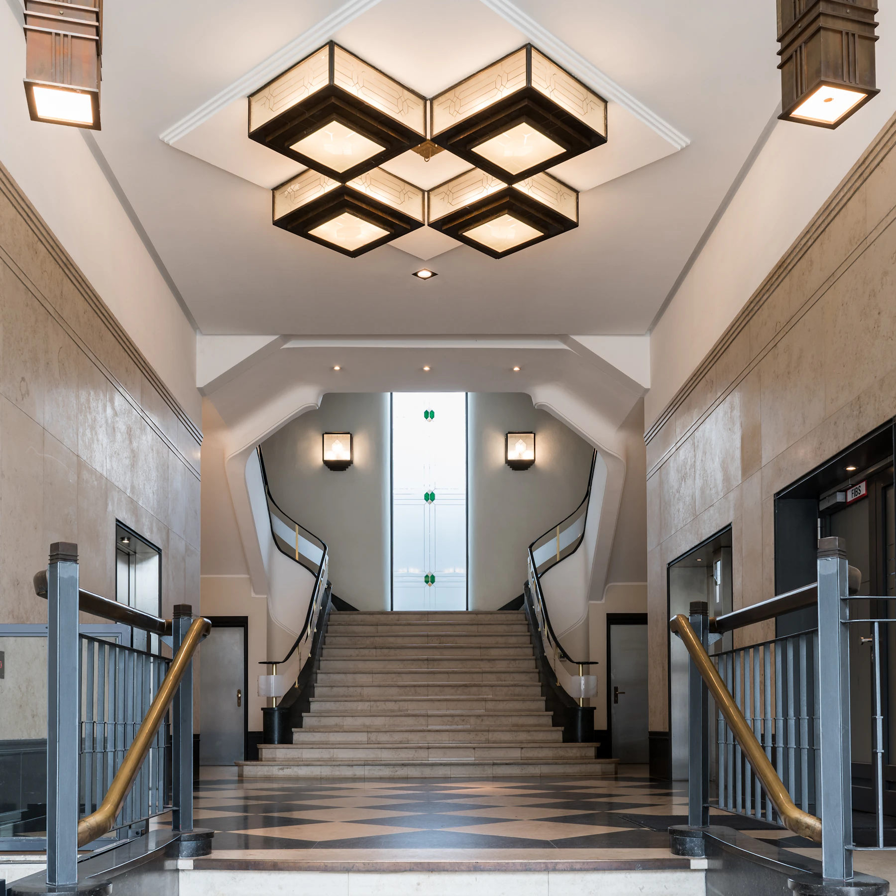 An art deco lobby and symmetrical staircase with geometric ceiling lights in Hamburg